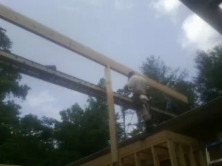 Carpenter setting a ridge beam over a new addition frame — Ice Dam Removal by Roofing Brothers in Gilbertville