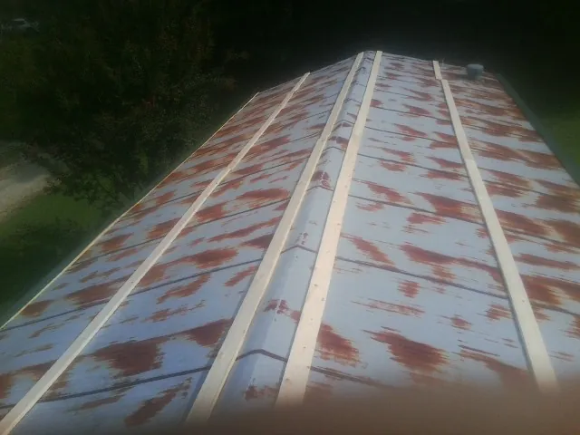 Rusted metal roof panels with new wood purlins before replacement — Storm Damage Roof Repair in Gilbertville by Roofing Brothers