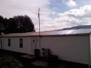 New metal roof on a single wide mobile home with a TV antenna in Gilbertville
