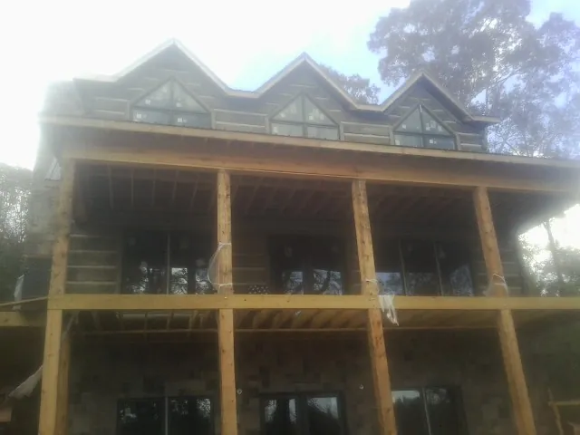 Dormers and porch framing on a large log home under construction — Roof Coating work by our crew in Gilbertville
