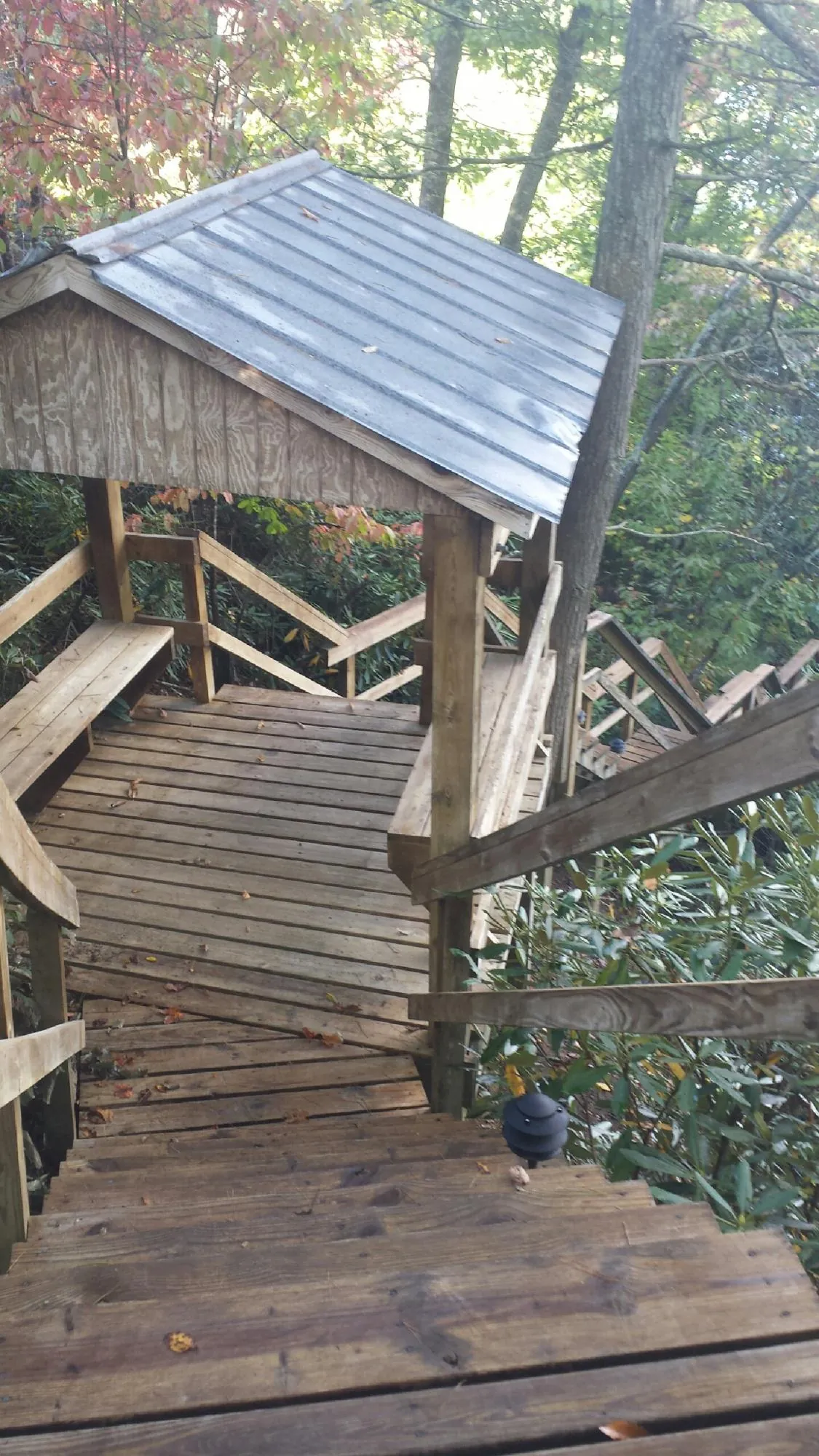 Metal roofed shelter over wooden steps on a wooded walkway — Skylight Repair & Installation work by our crew in Gilbertville
